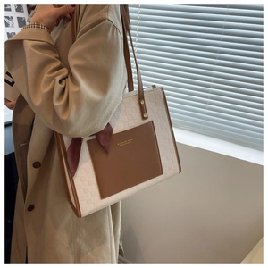 Detail of checkered tote bag with brown leather pocket and silk scarf on a model
