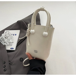 Close-up of cream leather mini bucket bag with spherical handle and woven ornament detail