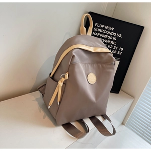 Detail of a minimalist waterproof nylon backpack with leather logo and contrast straps