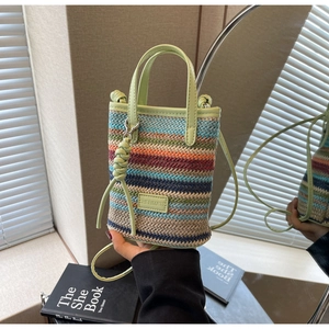 Detail of colorful striped straw woven mini bag with green leather handle and ball clasp