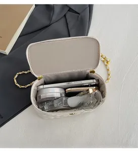Top view of white quilted vanity bag interior showing phone, perfume and cosmetics items