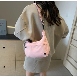 Détail du sac bandoulière en nylon rose cerise avec sangle à boucle réglable et poche zippée