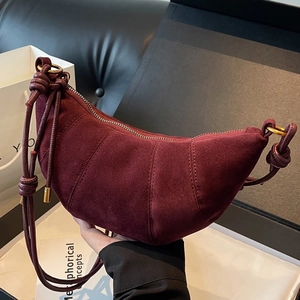 Fashionable burgundy suede croissant bag with decorative stitching and knotted strap