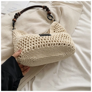 Détail d'un sac cabas en paille tissé main avec poignées en perles de bois et anneaux