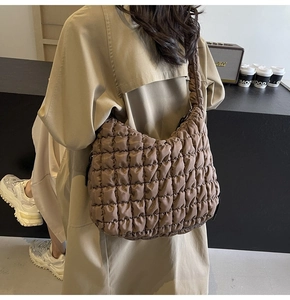 Close-up of a dark brown quilted cloud bag featuring soft bubble texture and wide strap