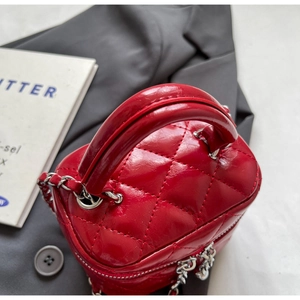 Macro shot of red quilted vanity bag with silver chain strap and top handle detail