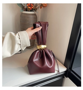 Detail van bordeauxrode cloud bag met zachte leren plooien en grote gouden metalen ring