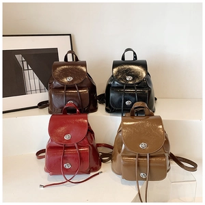 Detail showing vintage glossy mini backpacks in black, red, and brown with metallic clasps