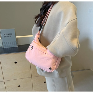 Sac bandoulière rose en nylon porté par un mannequin dans un décor intérieur chaleureux