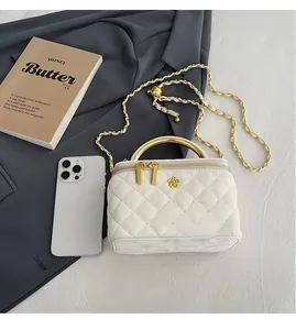 Macro detail of white quilted crossbody bag with gold metal handle and chain strap