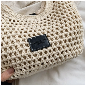 Détail macro du sac cabas tissé crème avec logo en cuir noir et texture en maille filet