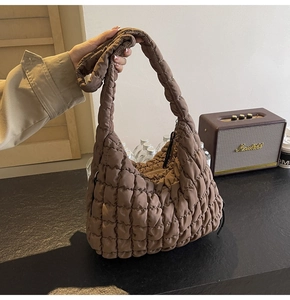 Detail shot of brown quilted puffy cloud bag showing soft texture and shoulder strap