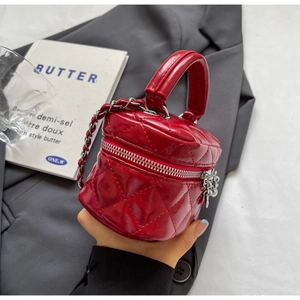 Detail of red quilted mini box bag with silver chain strap held in hand for size