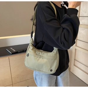 Détail du sac demi-lune en nylon vert clair avec bandoulière réglable et zip latéral
