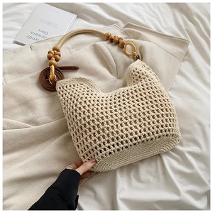 Gros plan d'un sac cabas tissé crème avec poignée en perles de bois et bandoulière brune