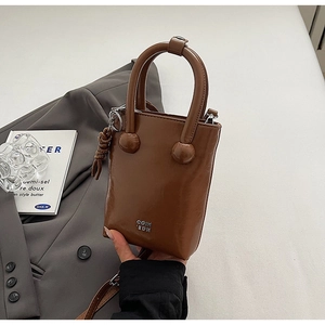 Close-up of brown textured leather handbag with silver logo and decorative knot detail