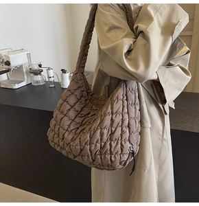 Macro detail of dark brown quilted puffer bag showing plush texture and wide strap