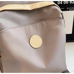 Close-up of gray waterproof nylon backpack fabric with beige leather logo patch