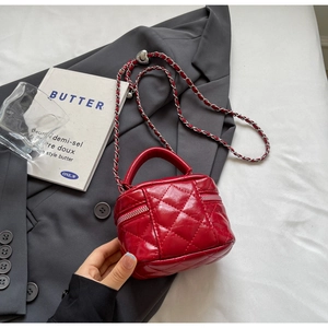 Close-up of red quilted patent leather mini bag with silver chain and dual zippers