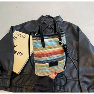 Detail of multi-color bohemian straw woven mini bucket bag with black leather straps