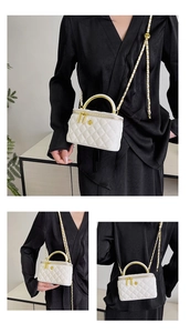 Detail of white quilted vanity bag featuring gold flower accent and chain strap