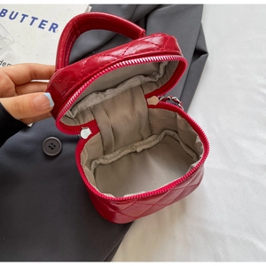 Detail view of red quilted mini bag showing the zipper closure and interior fabric lining