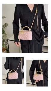 Detailed view of pink quilted mini box bag with gold handle and chain shoulder strap