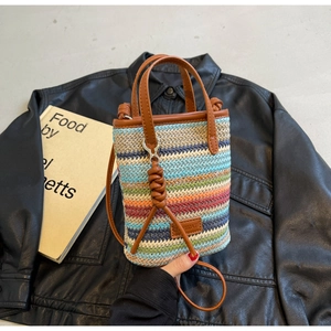 Detail of colorful woven straw bucket bag with brown leather handle and shoulder strap