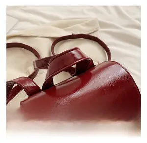 Detail show of the comfortable top handle on the burgundy glossy leather fashion backpack