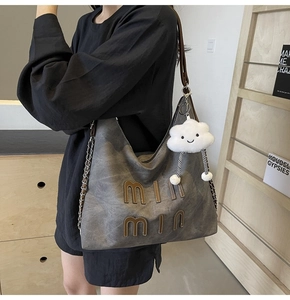 Close-up of large dark grey tote bag with letter embroidery and plush cloud charm