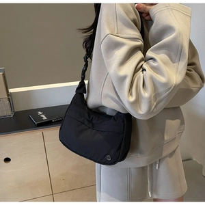 Détail du sac hobo en nylon noir avec bandoulière réglable et logo métallique discret