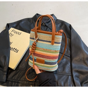 Close-up of colorful striped straw woven mini bag with brown leather handle and shoulder strap