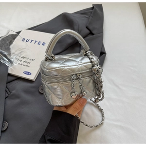 Detail view of silver mini quilted box bag with heart charm and metal chain strap