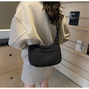 Détail du sac bandoulière noir en demi-lune avec sangle réglable et logo M en métal