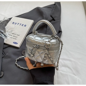 Close-up of silver quilted mini box bag with metallic texture and heart charm