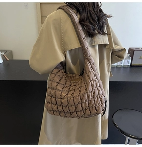 Detailed view of brown quilted bubble shoulder bag on model showing large capacity and texture