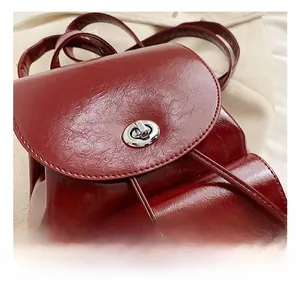 Close-up of silver oval twist lock and drawstring on wine red leather backpack