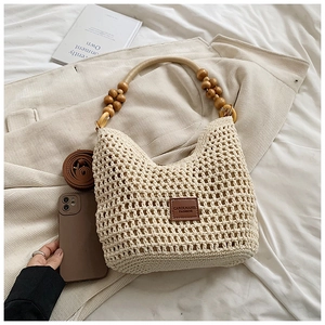 Détail du sac cabas en crochet beige avec poignées en bois et bandoulière en cuir brun