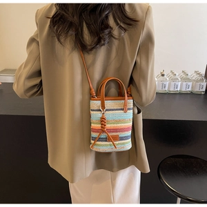 Detail of colorful woven straw bucket bag with brown leather handles and shoulder strap