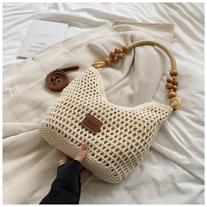 Détail du sac cabas en paille tissée beige avec poignée en bois et bandoulière en cuir