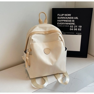 Detail view of cream nylon backpack with side pockets on white marble surface