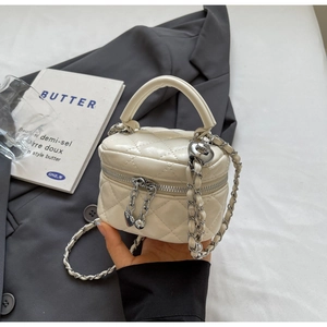 Detailed macro of a cream quilted mini box bag featuring silver heart zipper pulls