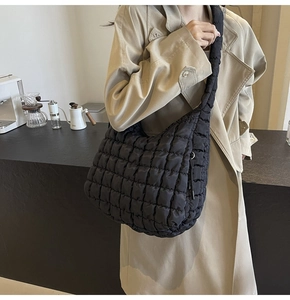 Close-up of a large black quilted puffy bag on shoulder with urban casual style