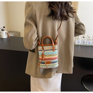 Detail of colorful striped woven mini bucket bag with leather handles and crossbody strap