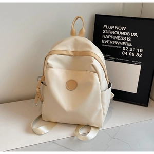 Detailed view of beige waterproof nylon backpack with light coffee trim on marble surface