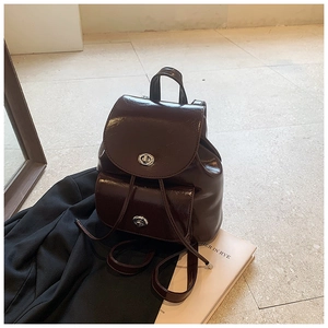 Detail of dark brown glossy leather backpack featuring silver metal turn-lock closures