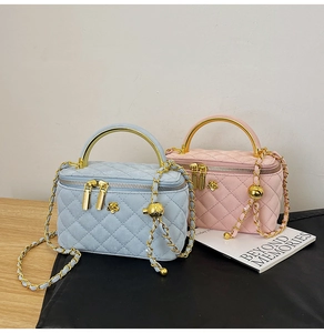 Detail of macaron quilted cosmetic bags with gold handles and chain straps on wooden table