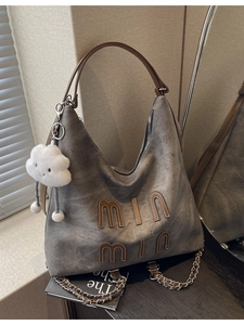 Gray washed leather tote bag with chain strap and cloud charm in a modern room setting