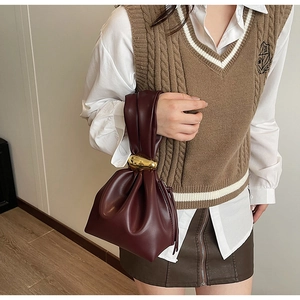 Detailweergave van bordeauxrode geplooide cloudbag met elegante gouden metalen beslag