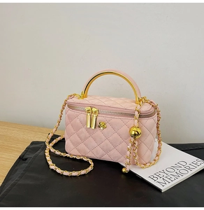 Detail of pink quilted chain bag with gold metal handle and camellia flower ornament